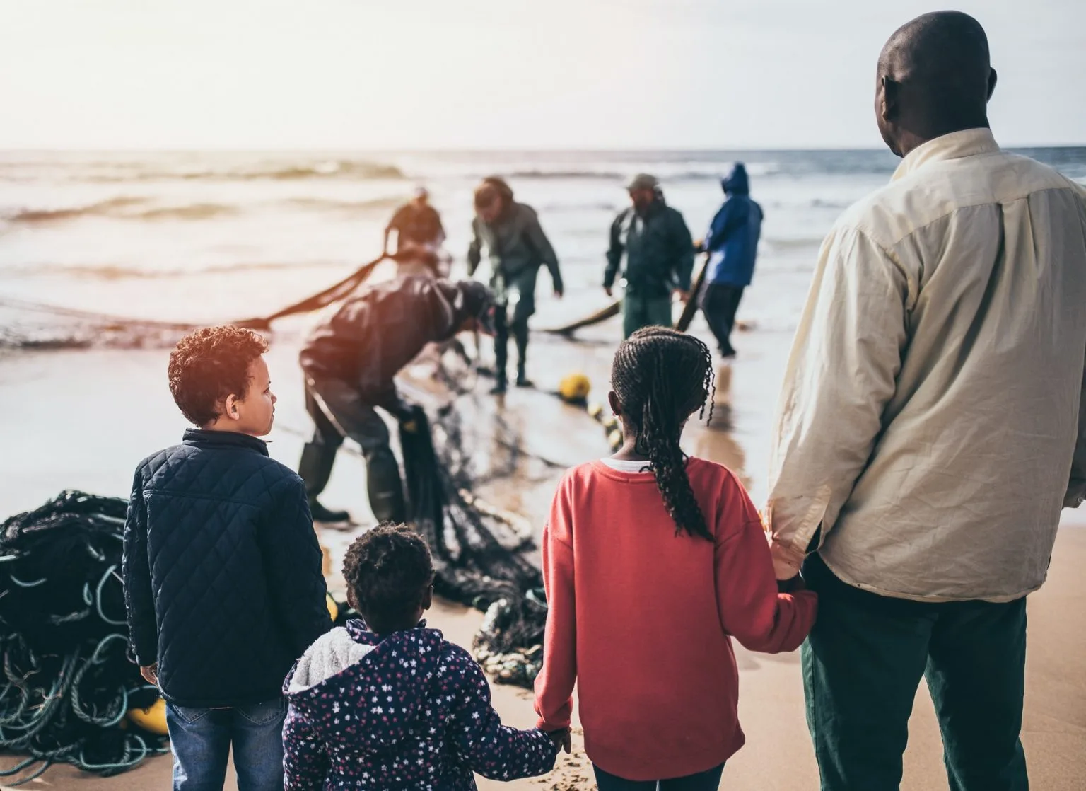 A family standing on a coastal beach watching community volunteers work together, 
            representing hope and unity for the Safe Haven Housing Trust.